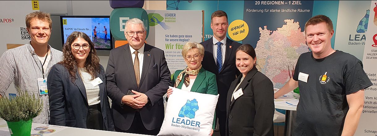 Sieben Personen am LEADER-Stand auf dem LWH. Drei Regionalmanager, Herr Wilhelm und die polnische Delegation sind zu sehen. Aufsteller im Hintergrund.