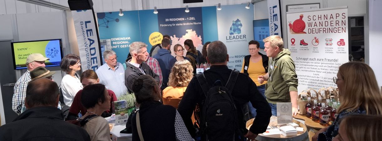 Viele Menschen versammeln sich am LEADER-Stand auf dem LWH. Aufsteller im Hintergrund.